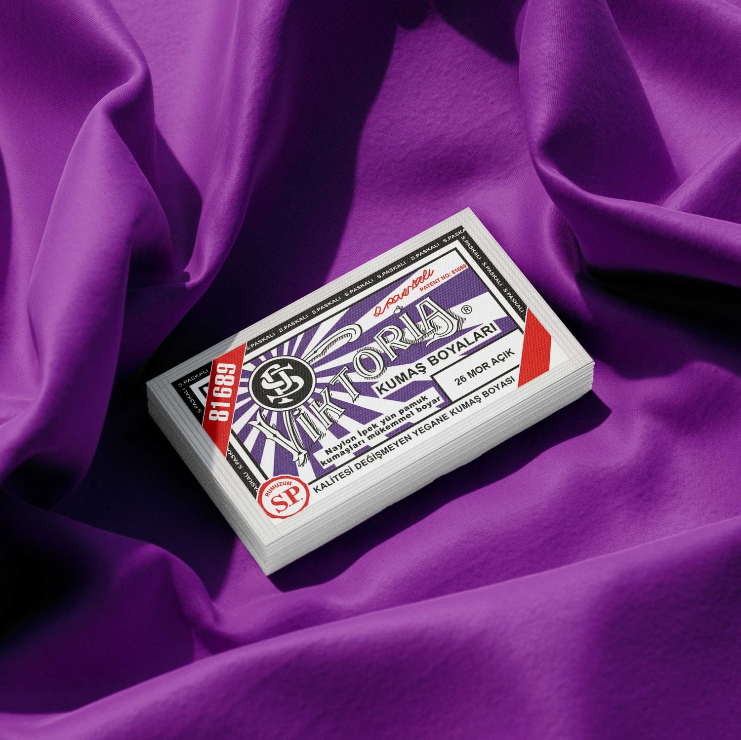 Pack of plum purple fabric dye placed on a vibrant purple fabric background